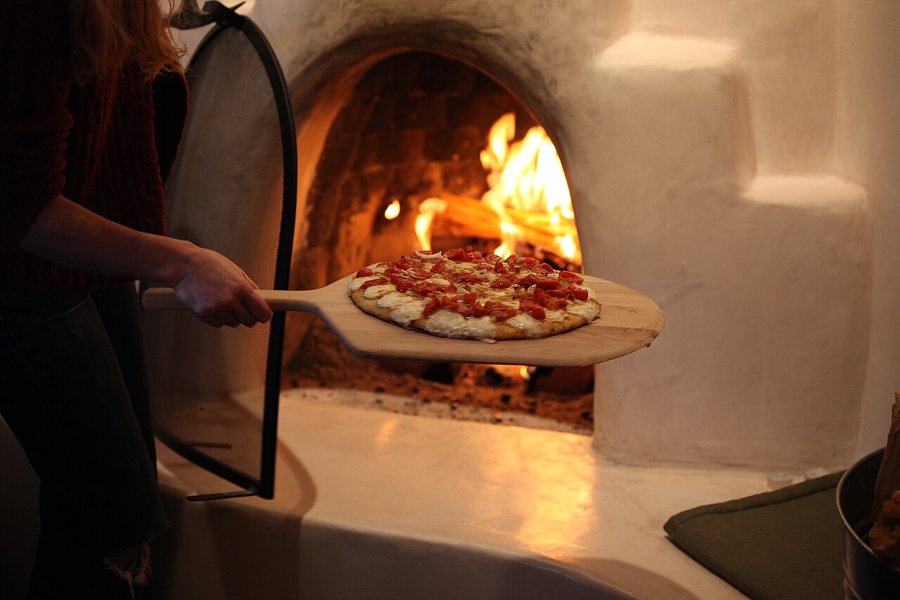 Una pizza appena infornata nel forno a legna